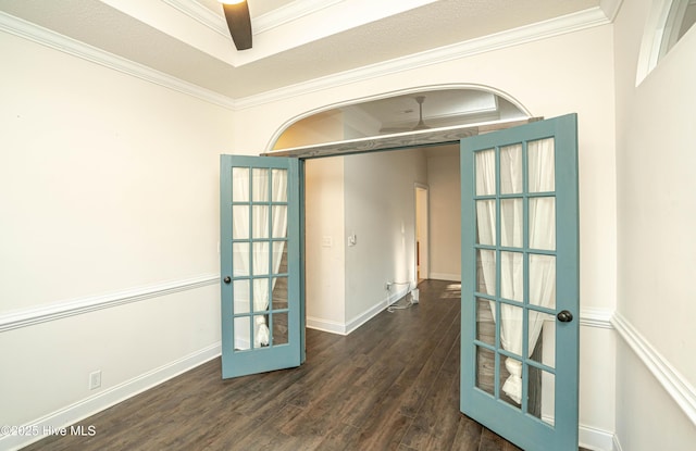 empty room featuring ceiling fan, french doors, dark wood-type flooring, and ornamental molding