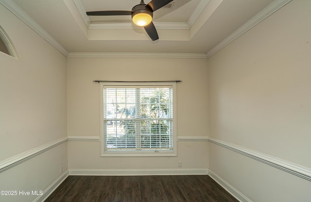 empty room with a raised ceiling, ceiling fan, dark hardwood / wood-style floors, and ornamental molding