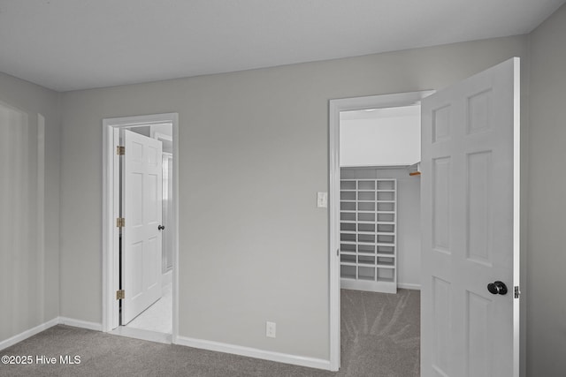 unfurnished bedroom with a spacious closet, a closet, and carpet