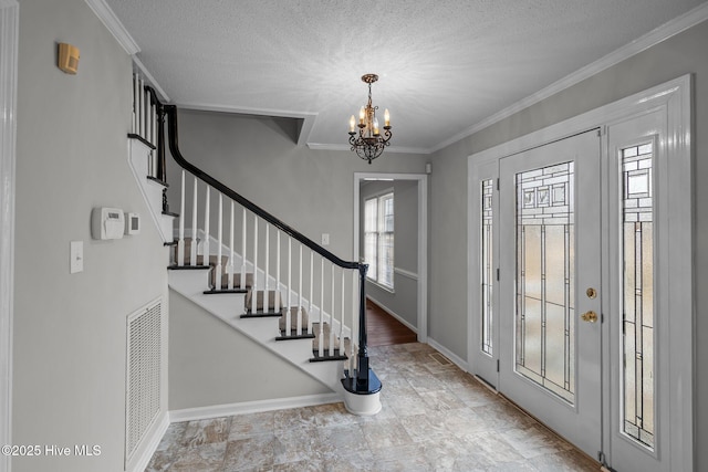 foyer with plenty of natural light, ornamental molding, and an inviting chandelier