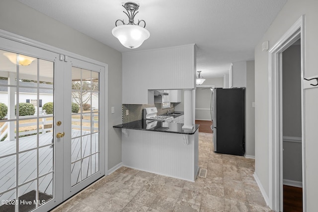 kitchen with white cabinets, stainless steel fridge, kitchen peninsula, and range with electric stovetop