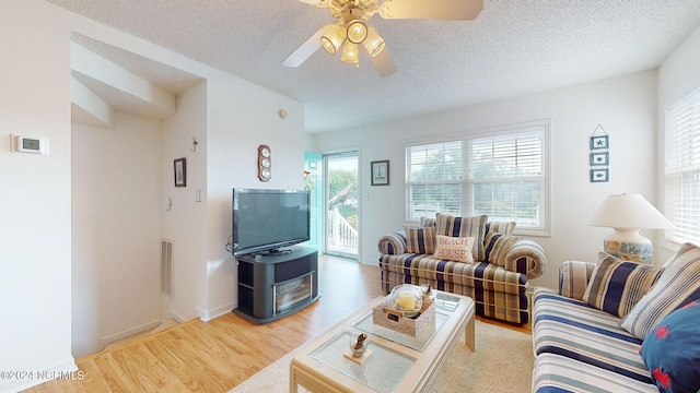 living room featuring hardwood / wood-style floors, ceiling fan, and a textured ceiling