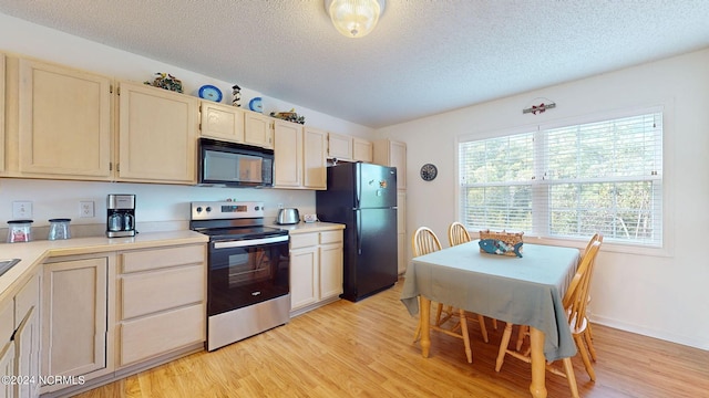 kitchen with light wood-type flooring, a textured ceiling, a healthy amount of sunlight, black appliances, and pendant lighting