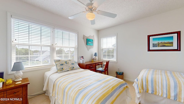 bedroom with ceiling fan, light colored carpet, and a textured ceiling