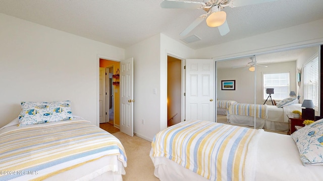 carpeted bedroom with ceiling fan, a closet, and a textured ceiling