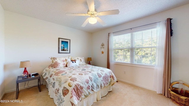 bedroom featuring ceiling fan, light colored carpet, and a textured ceiling