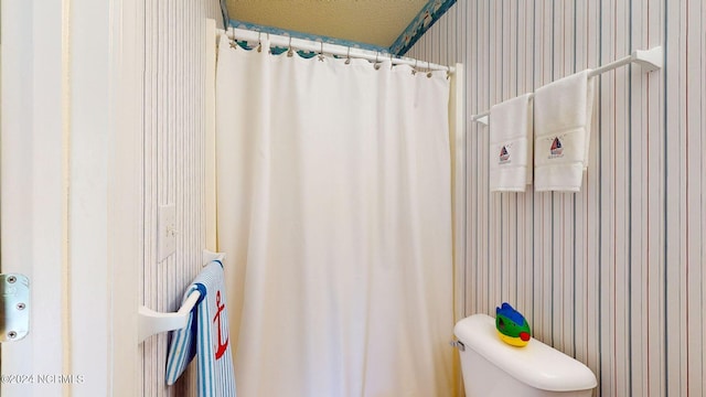 bathroom with a shower with curtain, a textured ceiling, and toilet