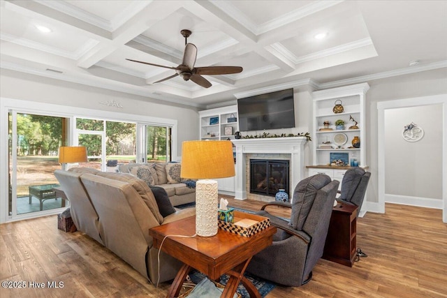 living area featuring a glass covered fireplace, beamed ceiling, and wood finished floors