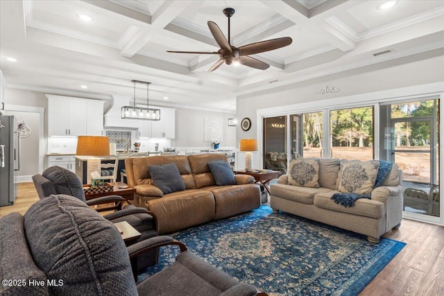 living area with beamed ceiling, a healthy amount of sunlight, visible vents, and light wood finished floors