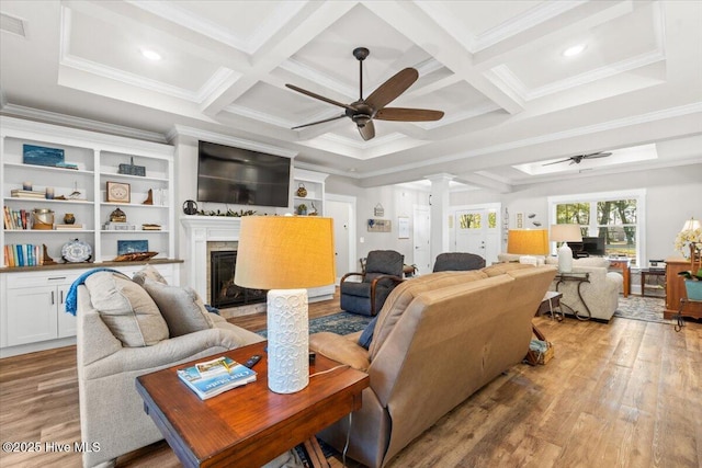 living area featuring coffered ceiling, light wood-style floors, ornate columns, and ceiling fan