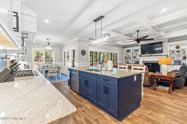 kitchen with beam ceiling, blue cabinetry, a sink, appliances with stainless steel finishes, and a glass covered fireplace