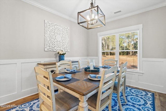 dining room featuring a wainscoted wall, crown molding, and wood finished floors