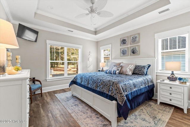 bedroom featuring visible vents, a raised ceiling, and multiple windows