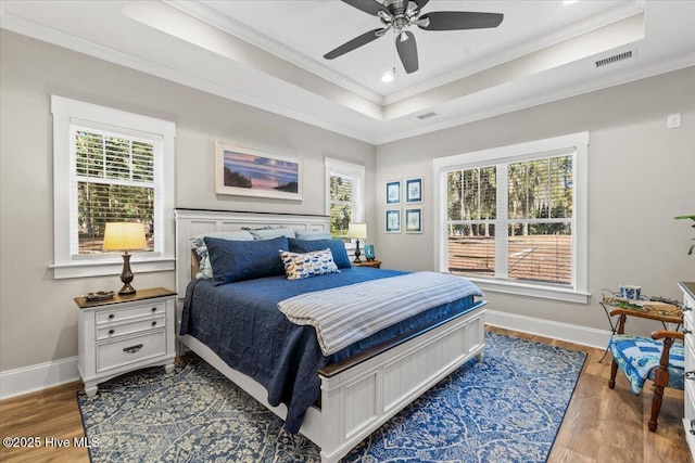 bedroom with visible vents, a raised ceiling, and wood finished floors