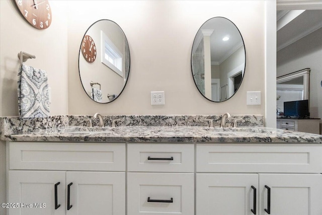 full bath featuring double vanity, crown molding, and a sink