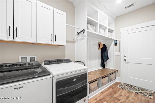 laundry area with light wood-style flooring, visible vents, cabinet space, and independent washer and dryer