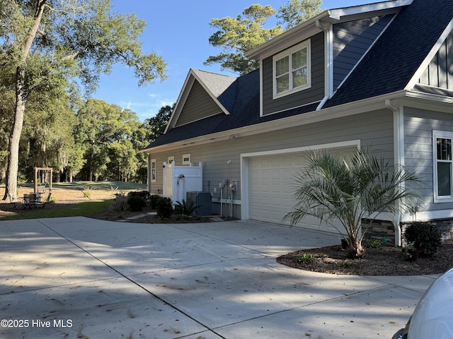 view of side of home featuring an attached garage, cooling unit, concrete driveway, and roof with shingles