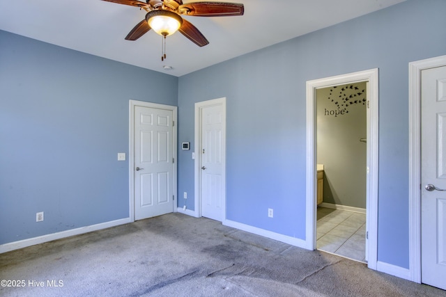 unfurnished bedroom with ensuite bath, light colored carpet, and ceiling fan