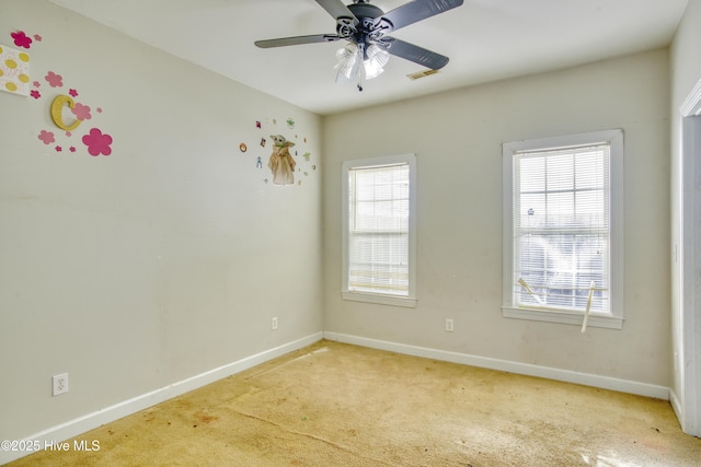 empty room with ceiling fan, light colored carpet, and a healthy amount of sunlight