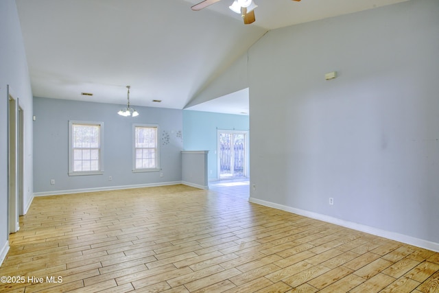 spare room featuring vaulted ceiling, ceiling fan with notable chandelier, and light wood-type flooring