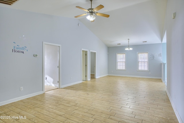 empty room featuring high vaulted ceiling, ceiling fan with notable chandelier, and light wood-type flooring