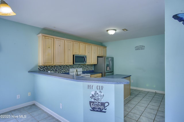 kitchen featuring appliances with stainless steel finishes, light tile patterned floors, decorative backsplash, and kitchen peninsula