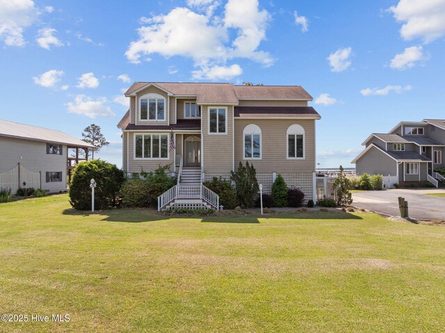traditional home featuring a shingled roof and a front lawn
