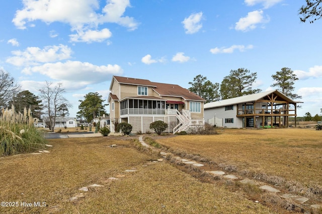 back of property with a deck, a yard, and a sunroom