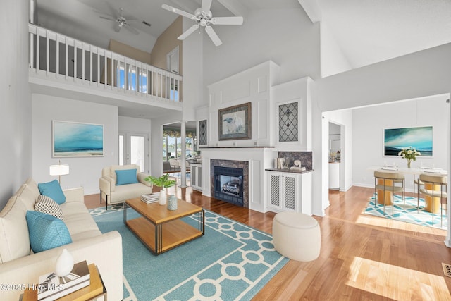living area featuring high vaulted ceiling, ceiling fan, a fireplace, and wood finished floors