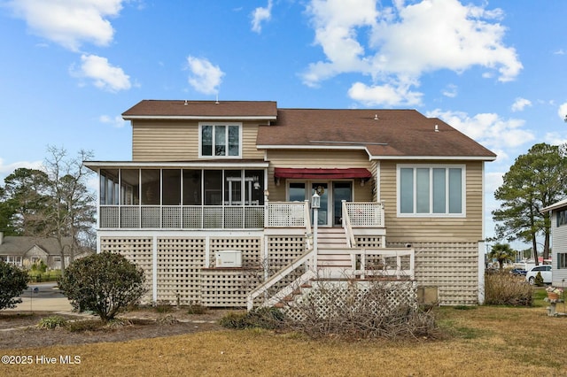 rear view of property with a sunroom and a lawn