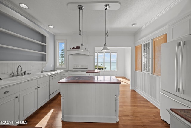 kitchen featuring open shelves, a kitchen island, white appliances, a sink, and a wealth of natural light