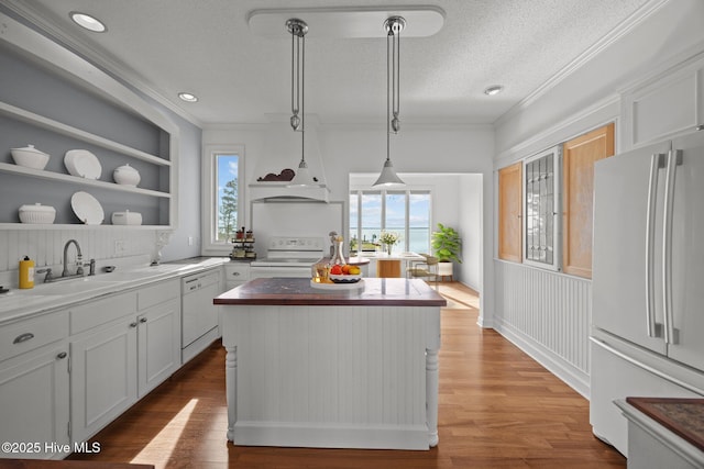 kitchen featuring a center island, open shelves, a sink, white appliances, and a wealth of natural light