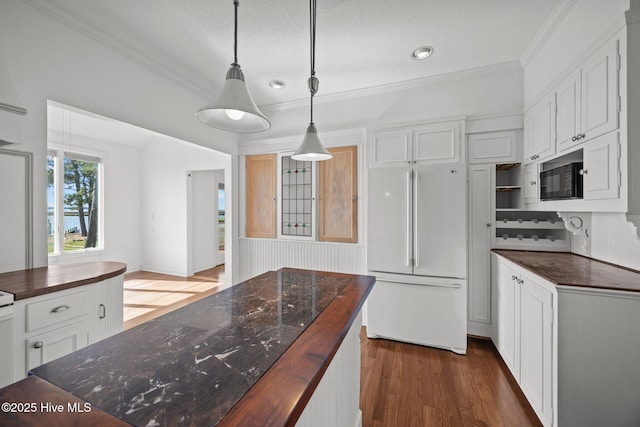 kitchen with crown molding, a textured ceiling, refrigerator, and wooden counters
