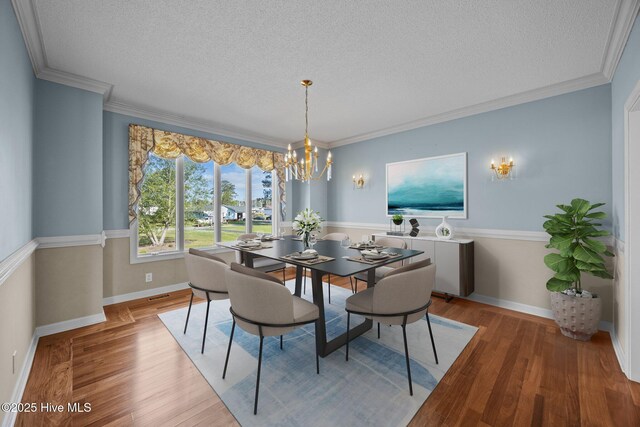 dining area with a textured ceiling, a notable chandelier, and light wood-style floors