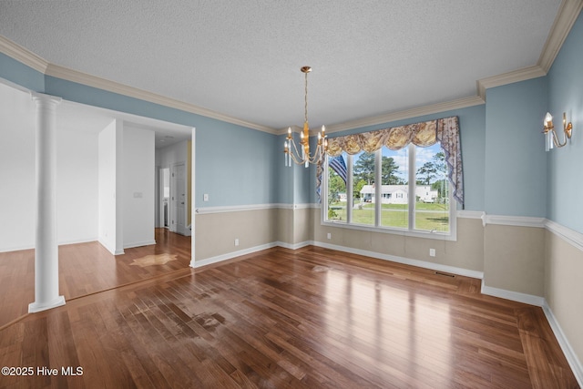 unfurnished dining area featuring crown molding, wood finished floors, baseboards, a textured ceiling, and a chandelier