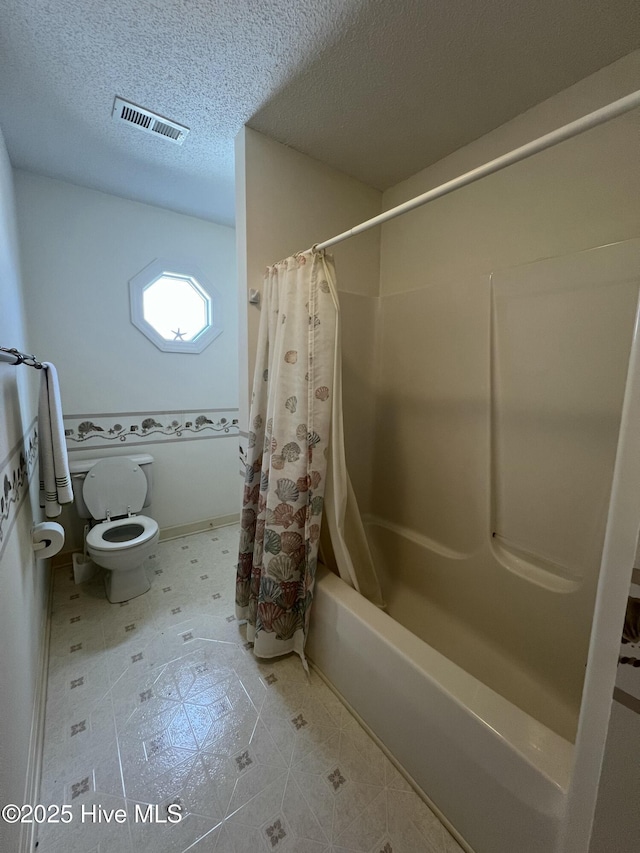 bathroom featuring a textured ceiling, toilet, and shower / bath combination with curtain