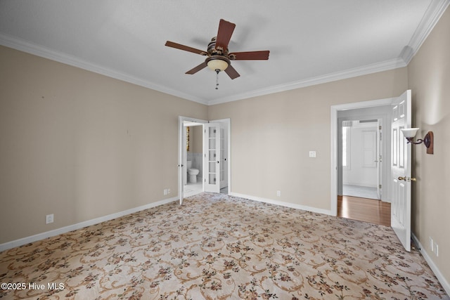 carpeted spare room with crown molding, baseboards, ceiling fan, and french doors