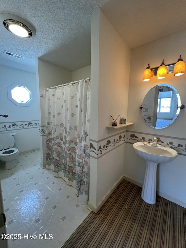 bathroom featuring a shower with shower curtain and a textured ceiling