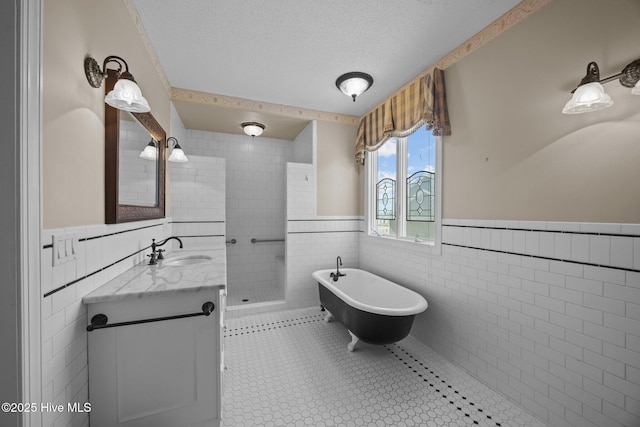 full bath with vanity, wainscoting, tile walls, a soaking tub, and a stall shower