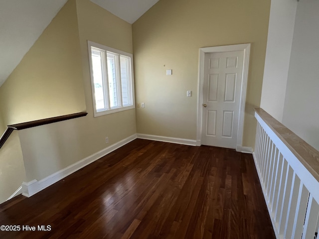 spare room with dark hardwood / wood-style floors and lofted ceiling