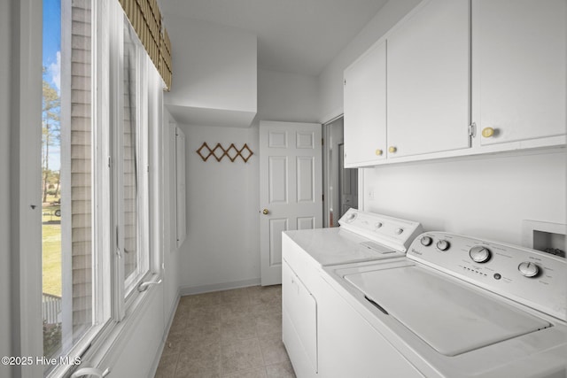 laundry area featuring cabinet space, light tile patterned floors, a healthy amount of sunlight, and washer and clothes dryer