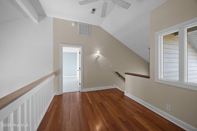 interior space with visible vents, vaulted ceiling, wood finished floors, baseboards, and an upstairs landing