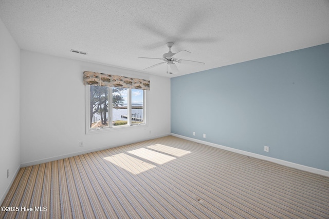 unfurnished room with carpet floors, a textured ceiling, ceiling fan, and visible vents