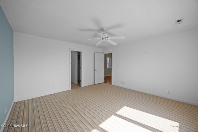 empty room featuring baseboards, light carpet, a ceiling fan, and visible vents