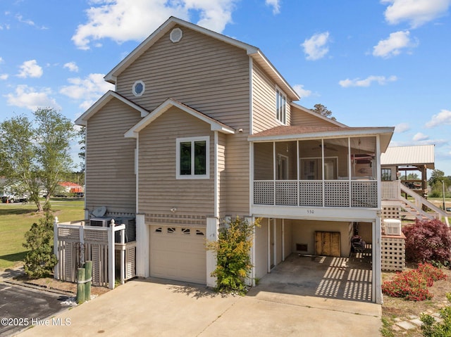 rear view of house with concrete driveway, a sunroom, and a garage