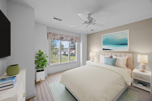 carpeted bedroom with a ceiling fan, a textured ceiling, and visible vents