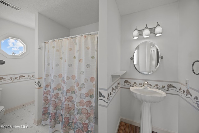 full bathroom featuring a textured ceiling, toilet, curtained shower, and visible vents