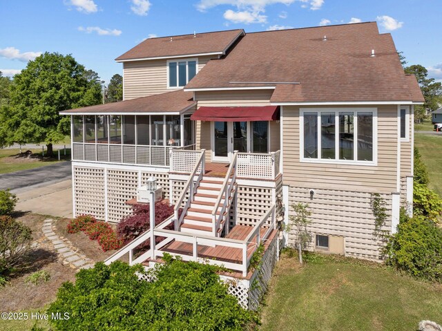 rear view of house with a sunroom, a shingled roof, a lawn, and stairway