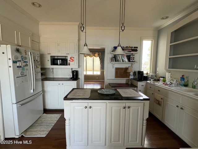 kitchen with decorative light fixtures, black microwave, a center island, and white fridge