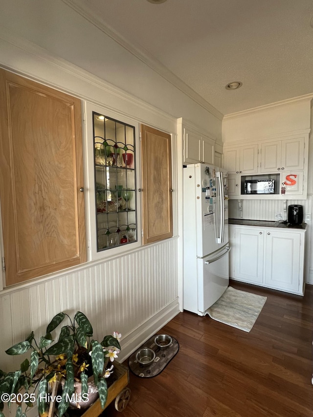 kitchen with white cabinets, crown molding, white fridge, and dark hardwood / wood-style flooring